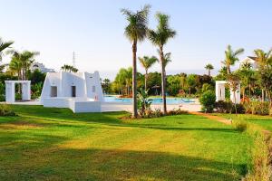 a resort with a pool and palm trees at Luxury Penthouse Alcazaba Lagoon 521 EHHouse in Estepona