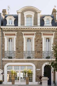 un gran edificio de ladrillo con ventanas y plantas blancas en B&B Maison Angélus en Saint-Malo