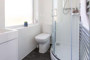 a white bathroom with a toilet and a shower at Studio Apartment with 65" Smart TV in Newport