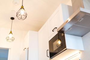 a kitchen with white cabinets and two lights at Studio Apartment with 65" Smart TV in Newport