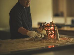 um homem a cozinhar comida em cima de um fogão em SOKI ATAMI em Atami