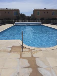 a swimming pool with blue water in a yard at Sous le soleil des Alpilles in Mouriès