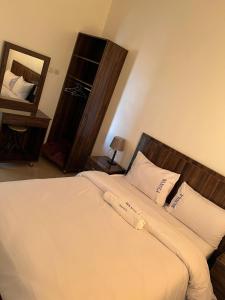 1 dormitorio con 1 cama con sábanas blancas y espejo en WANOLA APPART en Chichaoua