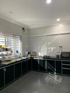 a large kitchen with black and white appliances at Johor home in Johor Bahru