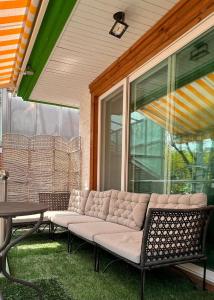 un sofá sentado en un porche junto a una ventana en Hongdae Luxury Private Single House with Big Open Balcony Perfect for a Family & Big Group 3BR, 5QB & 1SB, 2Toilet en Seúl