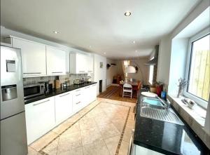 a large kitchen with white cabinets and a table at *Family Home in Mumbles. Close to the Beach* in The Mumbles