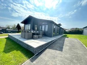 a small black house with a patio in a yard at *Luxury holiday home with hot tub close to beach* in Pembrokeshire