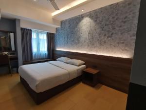 a bedroom with a bed and a stone wall at Lumut Hotel in Lumut