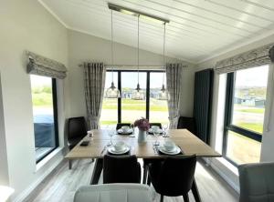 a dining room with a table and chairs and windows at *Luxury holiday home with hot tub close to beach* in Pembrokeshire