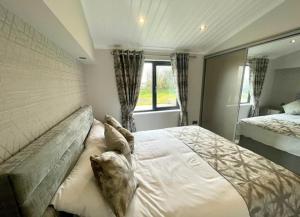 a bedroom with a large bed and a window at *Luxury holiday home with hot tub close to beach* in Pembrokeshire