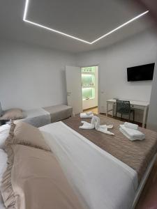 a white room with two beds and a desk at La dimora degli scrittori in Porto Empedocle