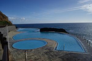 a swimming pool with the ocean in the background at Hotel Costa Linda in Porto da Cruz