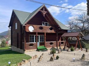 eine kleine Blockhütte mit einer Veranda und einem Pavillon in der Unterkunft Вілла в Карпатах in Worochta