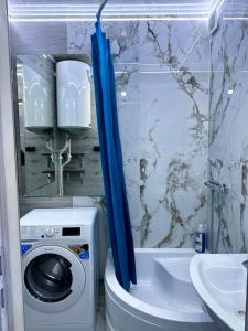 a bathroom with a washing machine and a blue shower curtain at Apartment in Chişinău