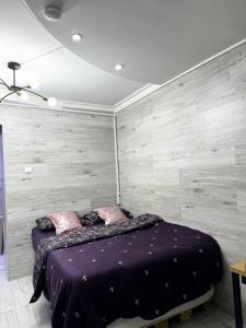 a bedroom with a purple bed with a wooden wall at Apartment in Chişinău