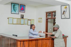 two people standing at a counter in a room at Kilimanjaro Crane Hotel in Moshi