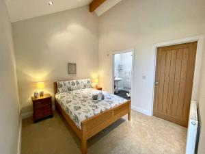 a bedroom with a bed and a door to a bathroom at Cosy barn with views in Wick Vale of Glamorgan in Wick