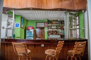 um bar com três cadeiras em frente a uma parede verde em Kilimanjaro Crane Hotel em Moshi