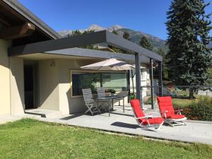 un patio con mesa, sillas y sombrilla en Alpinetouch, en Aosta