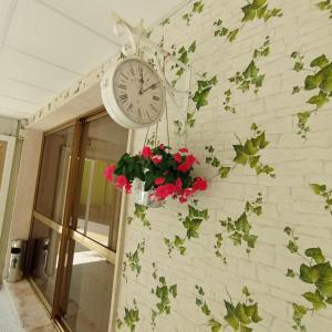 um relógio ao lado de uma parede com flores em Hotel Raul em Riccione
