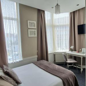 a bedroom with a bed and a desk and windows at Hotel 't Witte Huys Scheveningen in Scheveningen