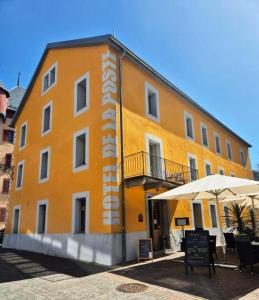 un gran edificio amarillo con una sombrilla delante de él en Hôtel de la Poste Sierre, en Sierre