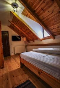 1 dormitorio con 1 cama grande en una habitación con suelo de madera en Casa de Piatra en Porumbacu de Sus