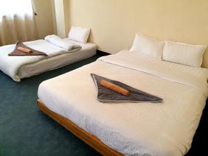 duas camas num quarto de hotel com toalhas em Hiti fusa em Pātan