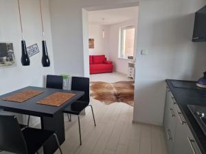 a kitchen and dining room with a table and a red couch at APARTAMENT NA POLNEJ in Ustka