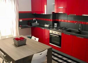 una cocina con armarios rojos y una mesa con fregadero en Casa Vacanze Manu, en Galatina