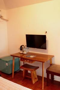 Habitación con mesa de madera y TV en la pared. en SAESEA Private Beach & Resort, en Karanghawu