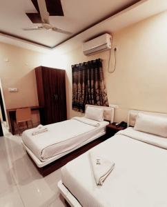 a bedroom with two beds and a window with a fan at WAY INN FAMILIAR in Hyderabad