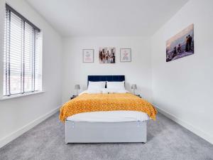Shindex Home Manchester في مانشستر: غرفة نوم بيضاء مع سرير ولحاف برتقالي