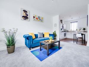 Shindex Home Manchester في مانشستر: غرفة معيشة مع أريكة زرقاء وطاولة
