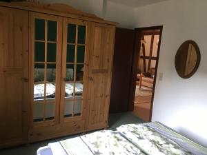 KamschlackenにあるDetached holiday residence in the wonderfully beautiful Harzのベッドの横に木製キャビネットが備わるベッドルーム1室が備わります。