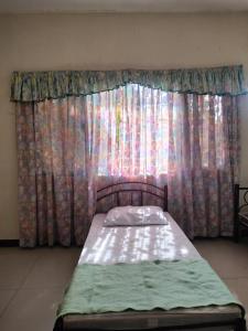 a bed sitting in front of a window with curtains at THE TAJ Inn in Cagayan de Oro