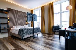 1 dormitorio con 1 cama, escritorio y ventanas en Hotel Zeezicht en Harlingen