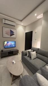 uma sala de estar com um sofá, uma mesa e uma televisão em هابي رومز em Al Khobar