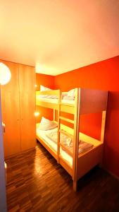 2 Etagenbetten in einem Zimmer mit orangefarbener Wand in der Unterkunft Ferienwohnungen "Adventure Panorama" Appartement Falken Top 8 in Warth am Arlberg