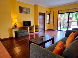 a living room with a couch and a tv at Baan Mesuk Hua Hin Spa and Resort in Hua Hin