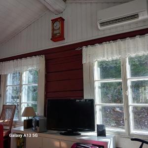 a living room with a tv and two windows at Cottage / Mökki, unique summer cottage in Vihti