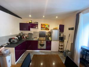 a kitchen with purple cabinets and a wooden table at Avélia Bonnevie in Murat