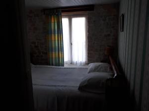 een slaapkamer met een bed en een raam met een regenboog gordijn bij maison grange in Sainte-Marie-de-Ré