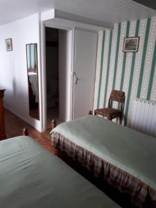 een slaapkamer met 2 bedden, een stoel en een spiegel bij maison grange in Sainte-Marie-de-Ré