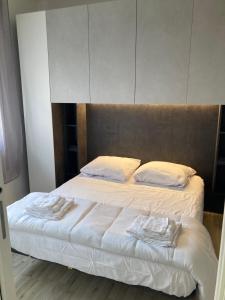 um quarto com uma cama com lençóis brancos e almofadas em Appartamento a 200 mt dal mare em Lido di Jesolo