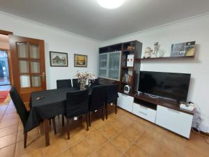 a dining room with a table and a flat screen tv at O Alecrin de Bouzas Ribeira Sacra in Pereiro de Aguiar