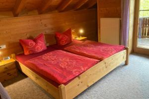 ein Holzbett mit roten Kissen in einem Zimmer in der Unterkunft Ferienwohnungen Bernie Schmid in Sonthofen