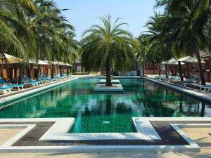 a swimming pool with palm trees and lounge chairs at Baan Mesuk Hua Hin Spa and Resort in Hua Hin