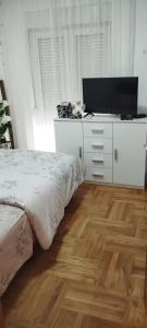 a bedroom with a bed and a flat screen tv at PremiumPlus Apartman in Vrnjačka Banja