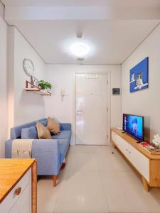 een woonkamer met een blauwe bank en een tv bij Madison Park Apartment Cozy Stay Near Central Park Mall in Jakarta
